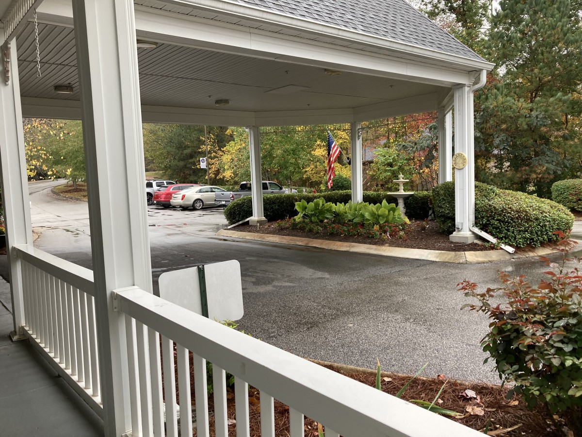 A covered carport with several cars parked nearby on an overcast day.