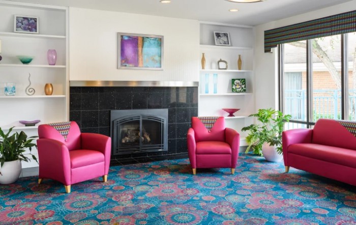 A colorful living room featuring red chairs, a fireplace, and decorative shelves.
