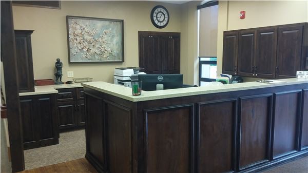 An office reception area with a wooden counter and office equipment.