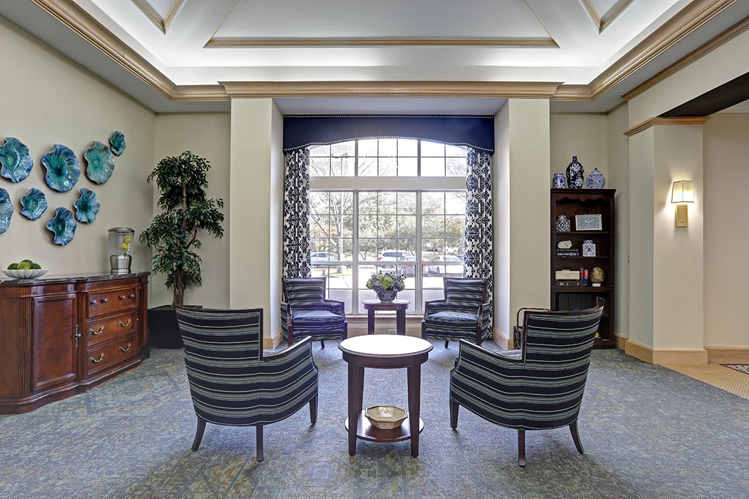 A cozy waiting area with elegant chairs and a central table in front of large windows.