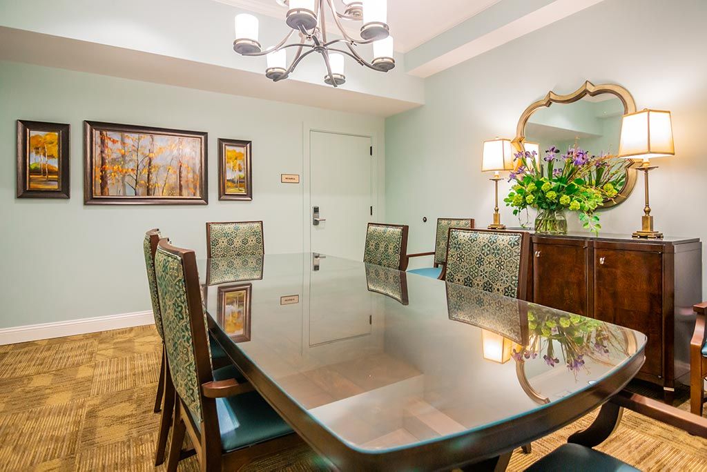 A well-designed dining room with a large table, elegant chairs, and a chandelier overhead.