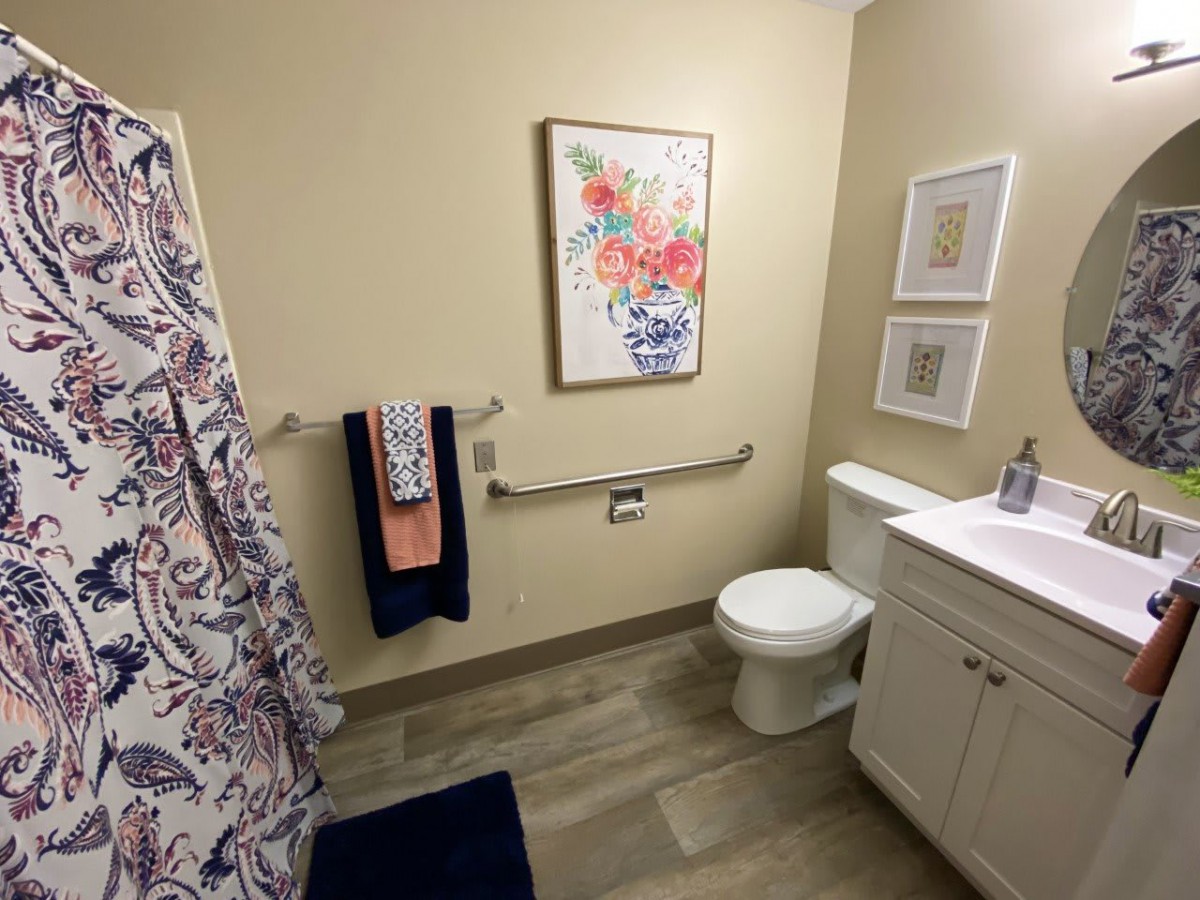 A clean and well-decorated bathroom with a floral-themed painting.