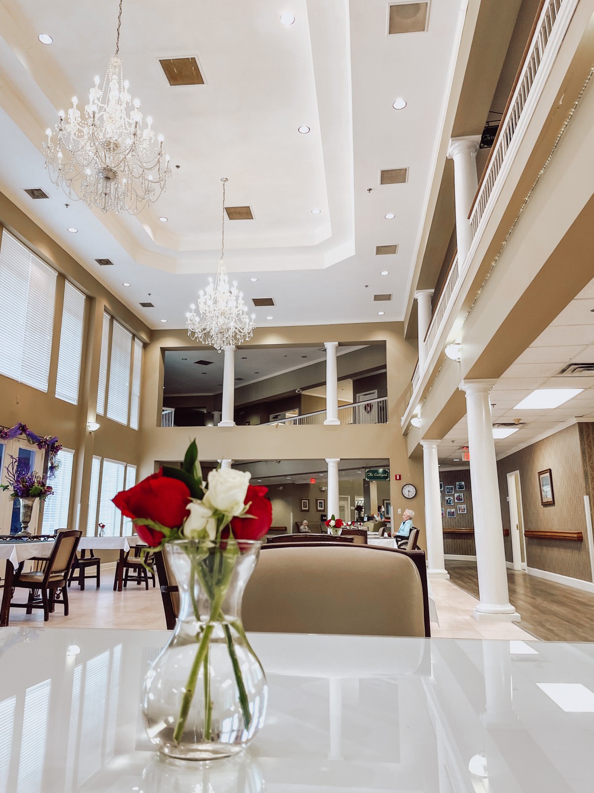 Luxurious interior with elegant chandeliers and a vase of roses on the table.