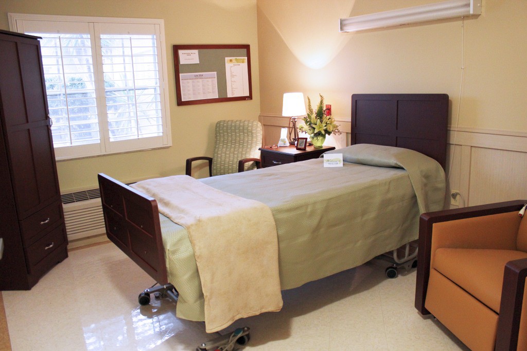 A clean and minimalist hospital room with a single bed and simple furnishings.