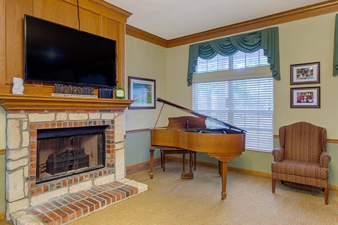 A cozy living room featuring a fireplace and a grand piano by the window.