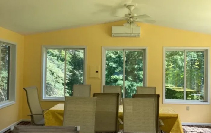 A bright dining room with a table and chairs, illuminated by natural light streaming through large windows.