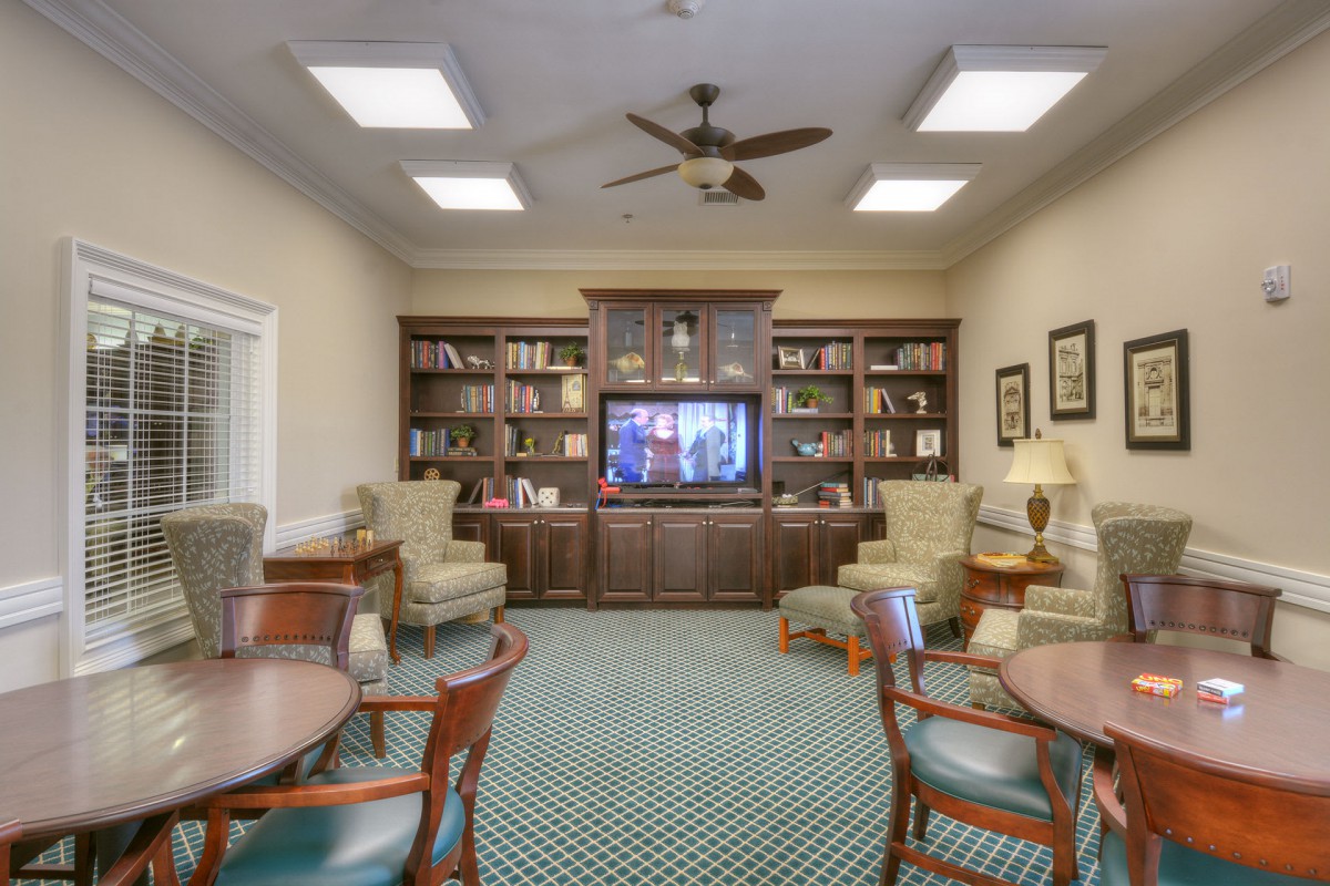 A cozy library room with bookshelves, seating, and a television.