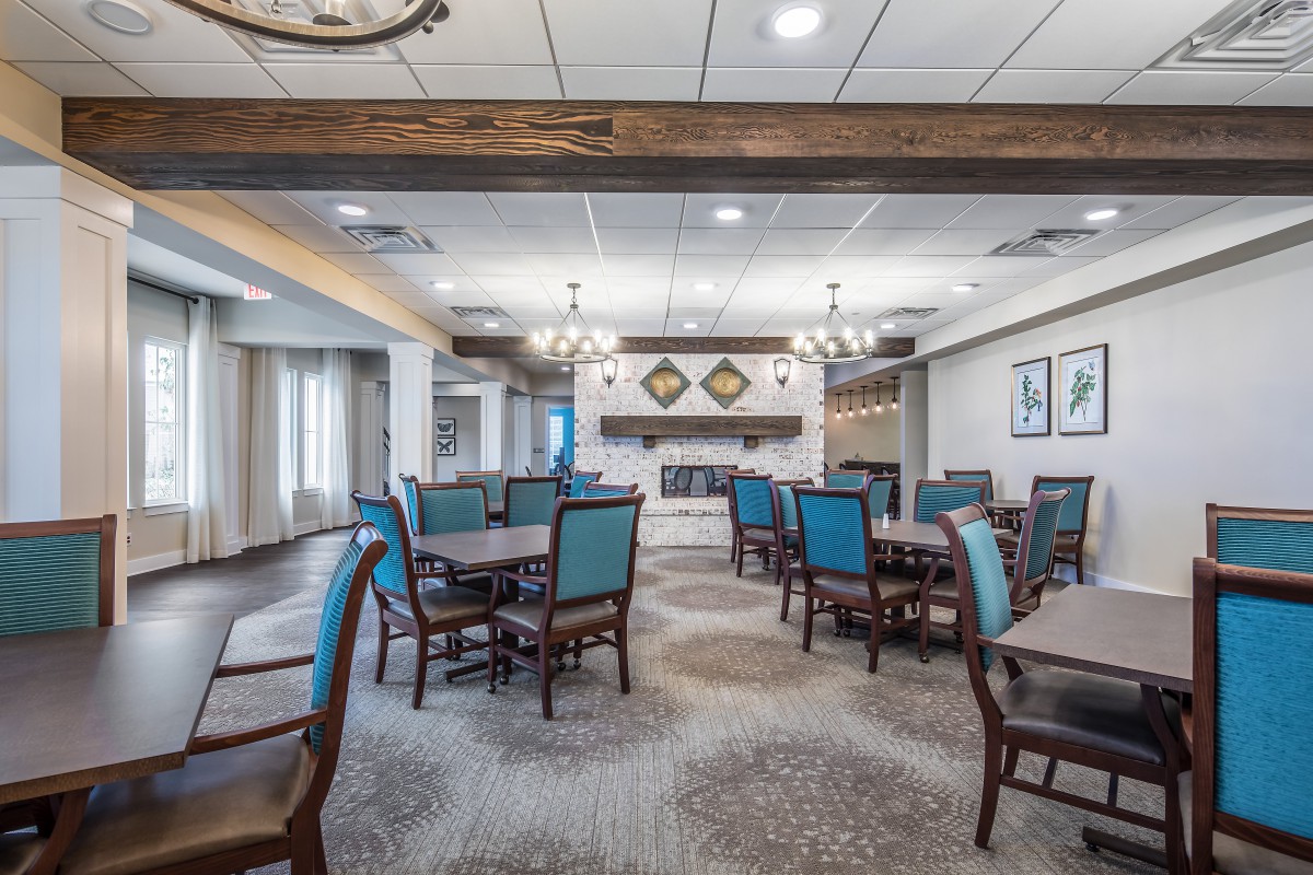 A spacious and elegantly designed dining room with multiple tables and chairs, featuring stylish lighting fixtures and decor.