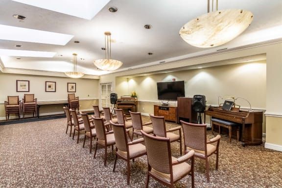 A well-lit conference room with rows of chairs facing a television and podium.