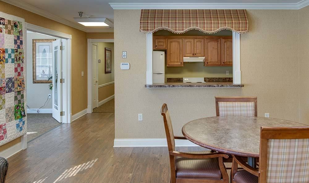 A cozy kitchen and dining area with wood flooring, featuring a round table and chairs.