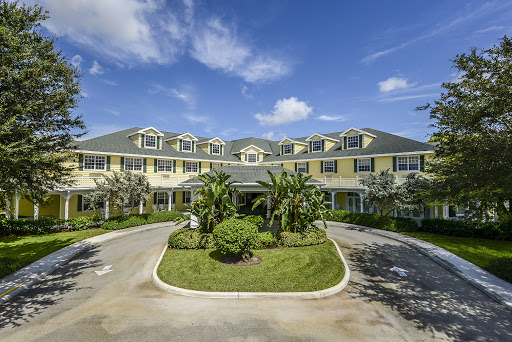 A charming hotel with a welcoming entrance surrounded by lush greenery under a clear blue sky.