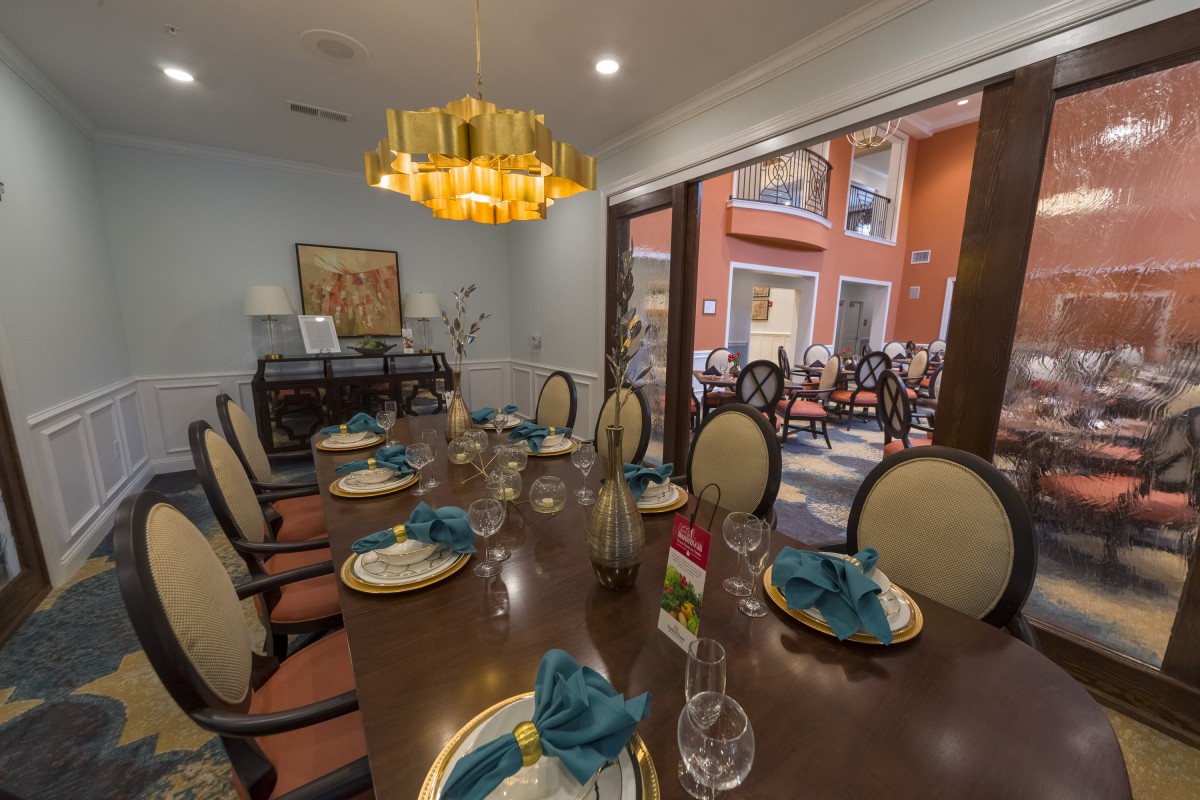 An elegantly decorated dining room with a large table set for a meal and a view of the outdoor patio through a glass door.