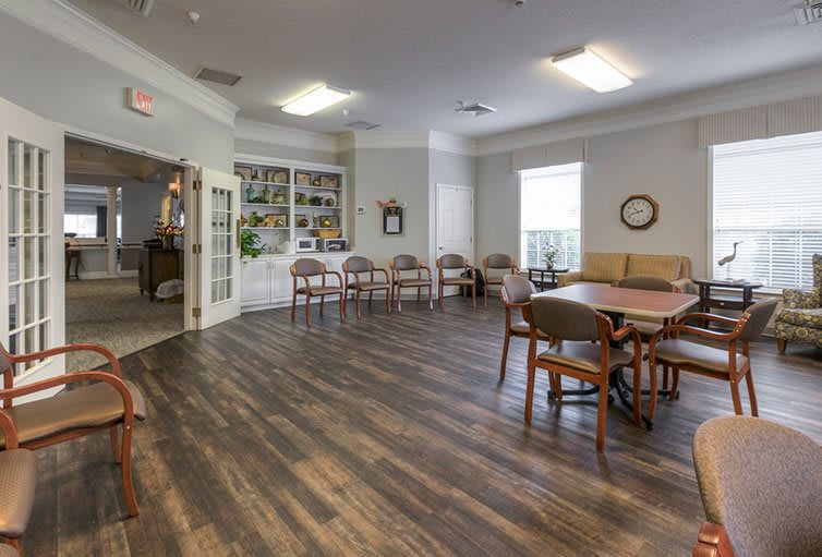 A cozy lounge area with wooden flooring, seating arrangements, and ample lighting.