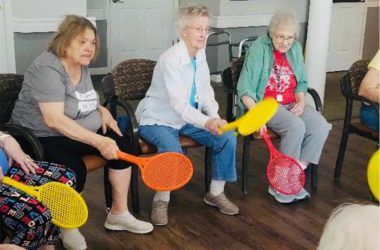 A group of seniors enjoying an indoor activity with colorful paddles.
