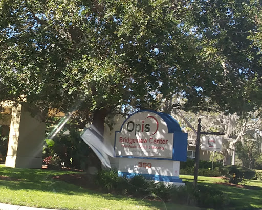 A sign indicating the presence of a residential community named 'Opus' surrounded by greenery.