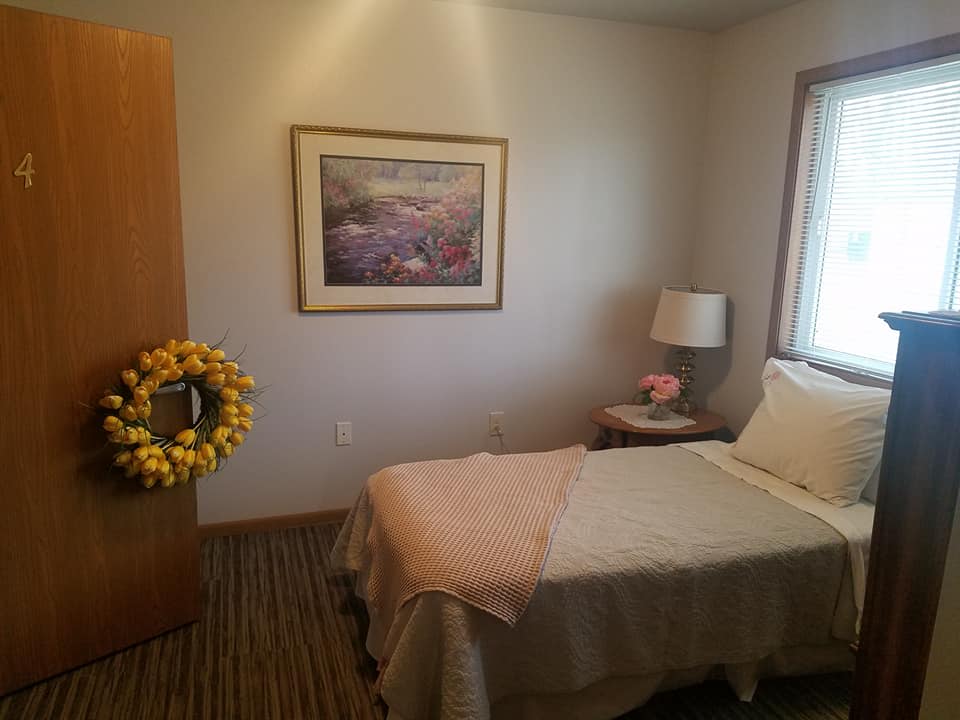 A cozy bedroom with a single bed, decorated with a lamp and a painting on the wall.