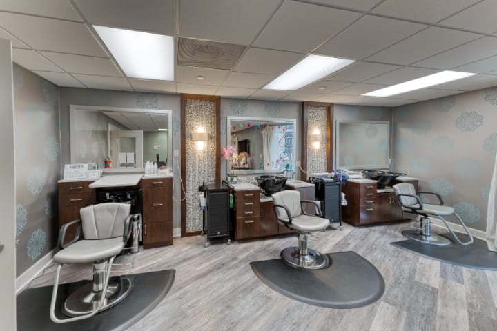A modern hair salon interior with multiple styling stations, comfortable chairs, and large mirrors.