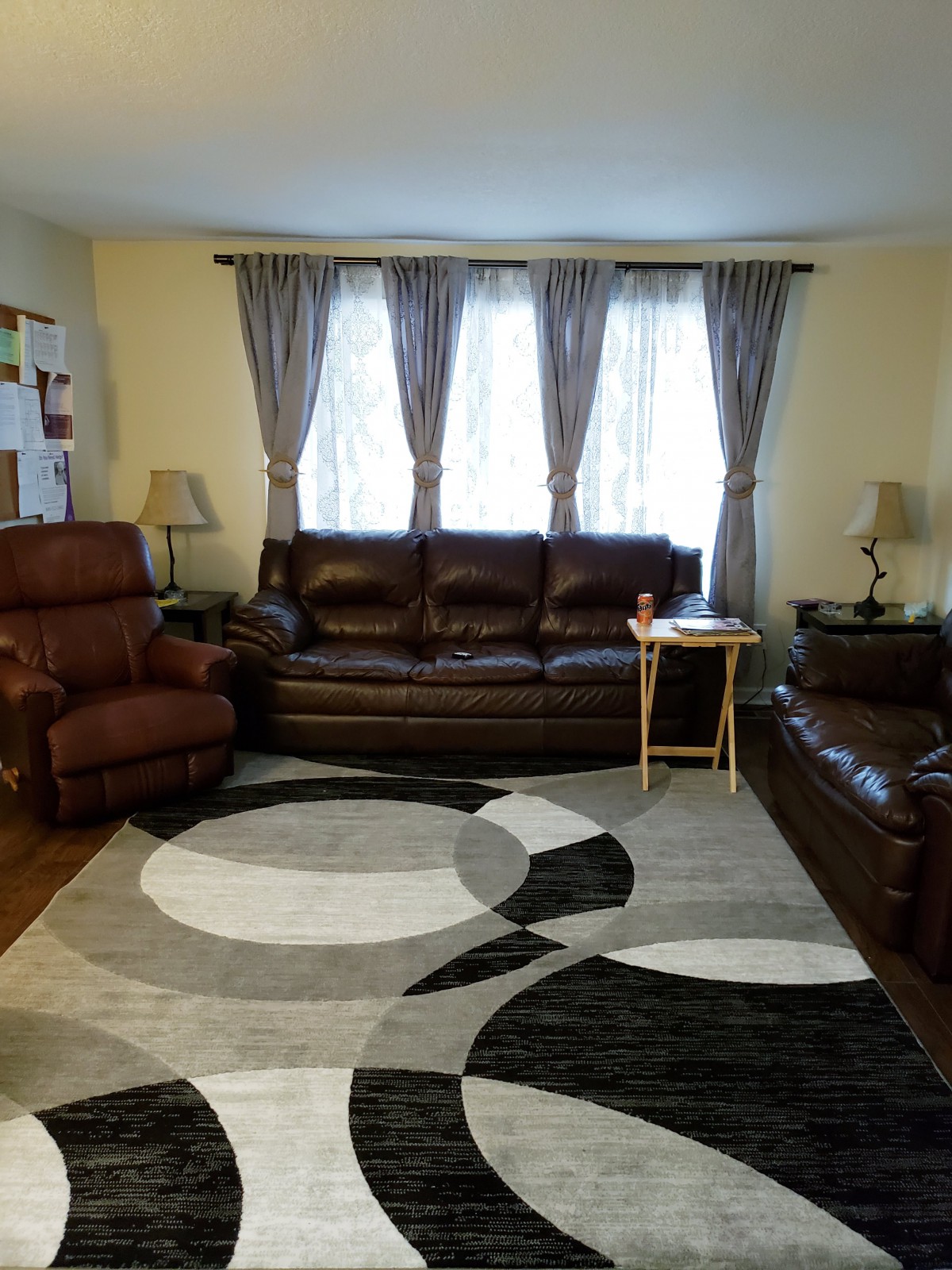 A cozy living room with sofas, an armchair, a geometric rug, and soft lighting.