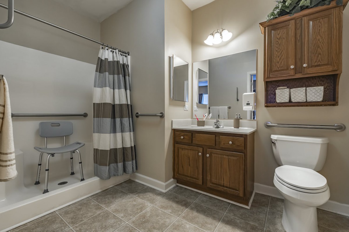 A modern bathroom with a shower, vanity, and wooden cabinetry.