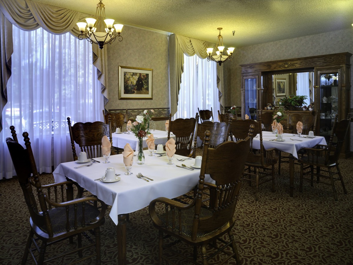 A cozy dining room with elegantly set tables and warm lighting.