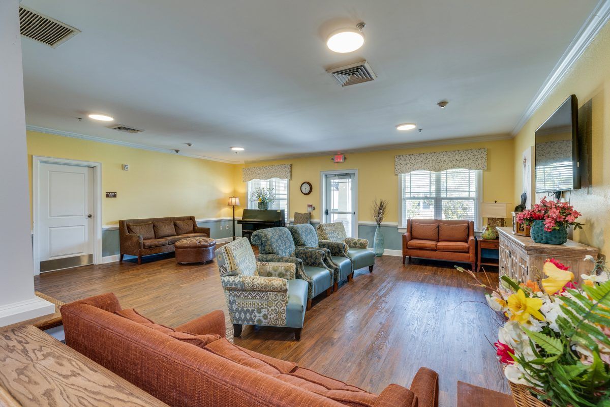 A spacious living room with multiple sofas and chairs, featuring warm lighting and wooden flooring.