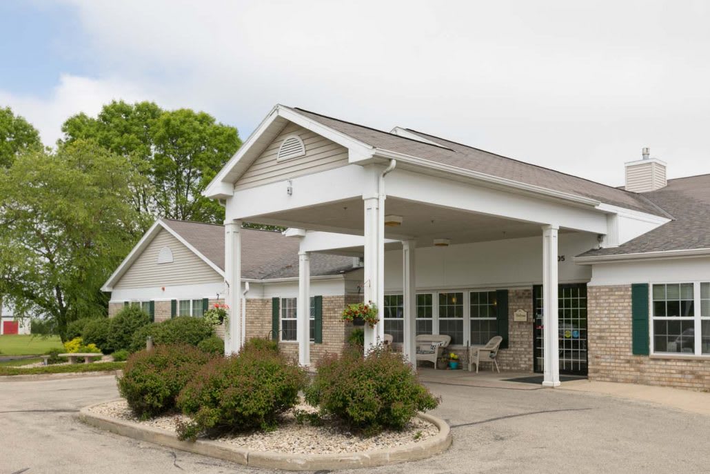 A front view of a building entrance with a covered porch and landscaped surroundings.