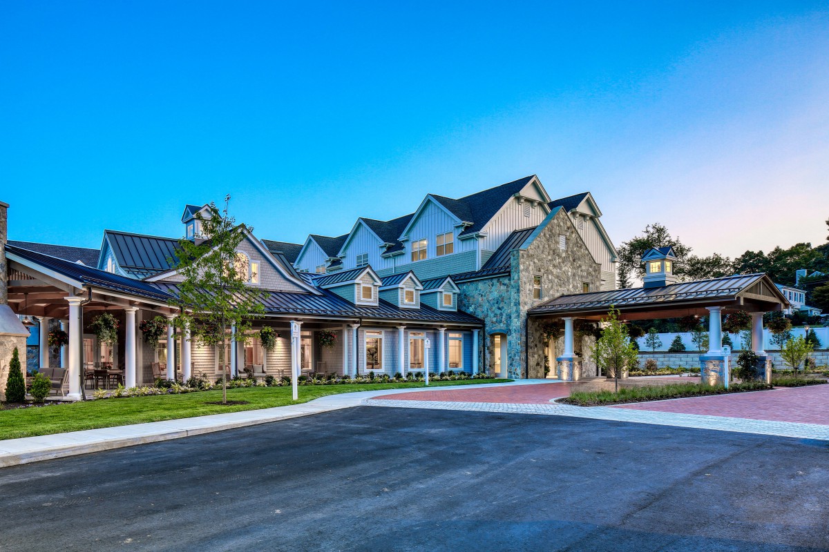 A beautiful residential building with a stone facade and lush landscaping under a clear blue sky.