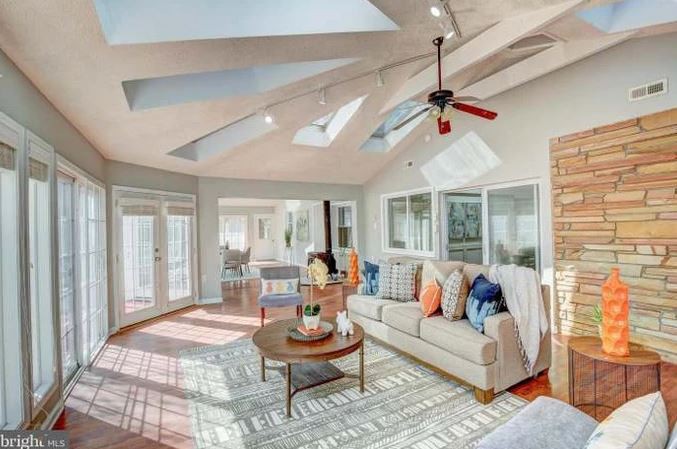 A bright and cozy living room with skylights, a sofa, coffee table, and ceiling fan.