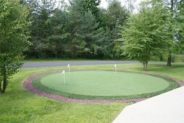 A small outdoor putting green surrounded by lush greenery and trees.
