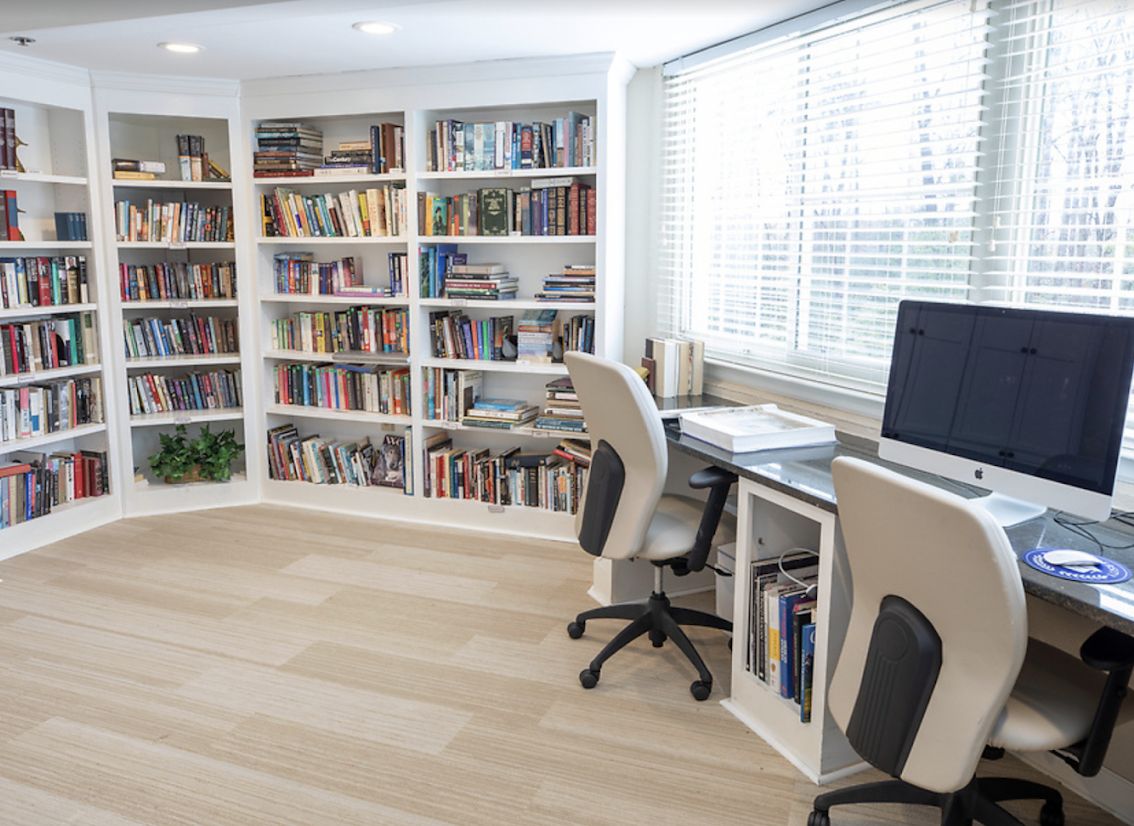 A bright and organized home office with bookshelves, a desk, and a computer setup by the window.