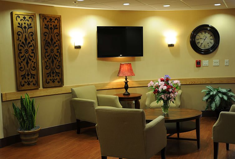 A cozy waiting room with comfortable chairs, a central table adorned with flowers, and ambient lighting.