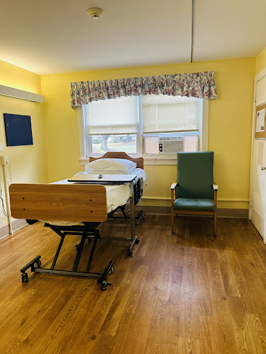 A hospital room featuring a patient bed, a chair, and bright yellow walls.