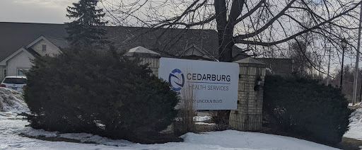 A sign for Cedarburg Health Services, visible in a snowy landscape.