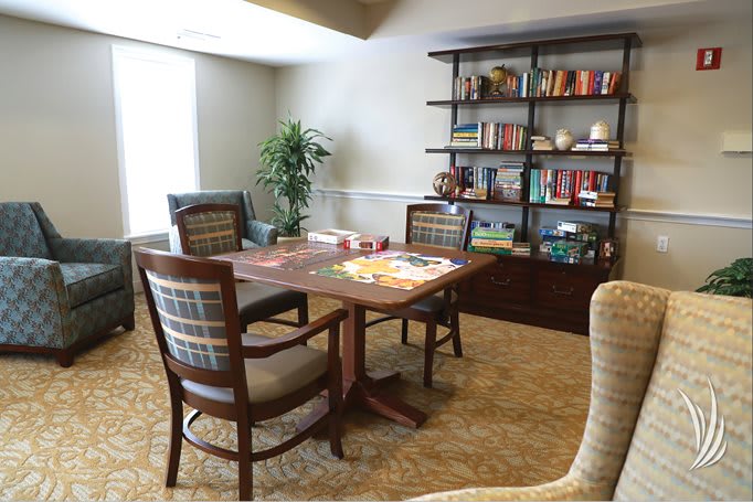 A cozy room with a wooden table, surrounded by chairs and a bookshelf filled with books.