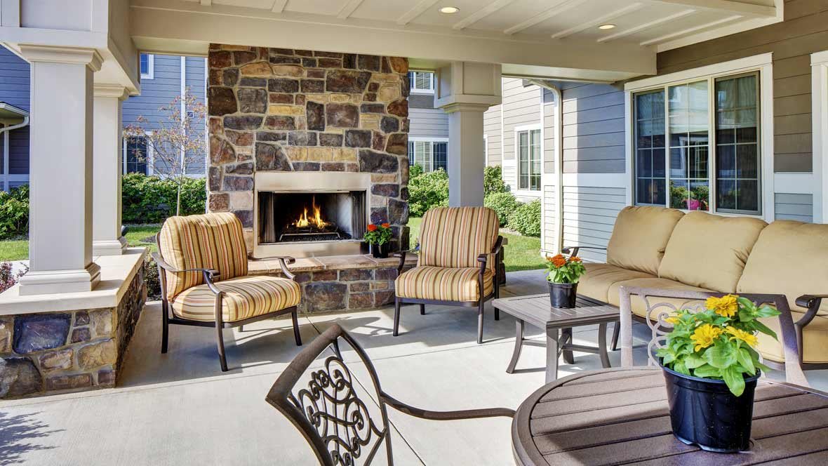A cozy outdoor patio with a stone fireplace and comfortable seating.