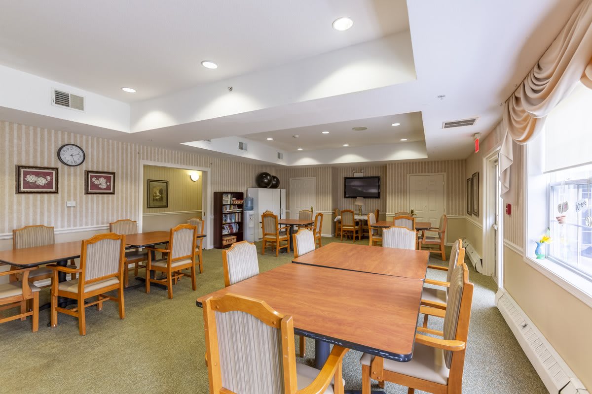 A well-lit dining area with wooden tables and chairs, featuring a cozy interior design.