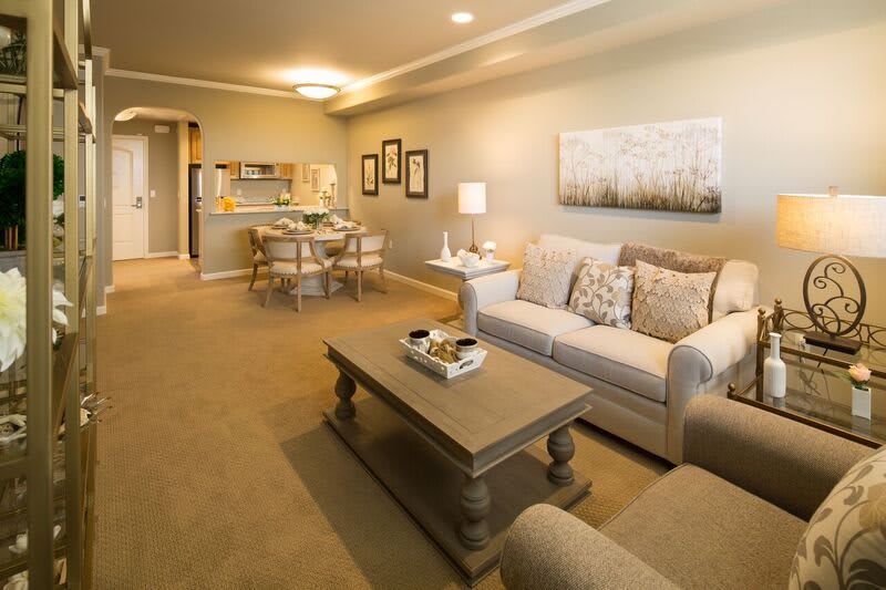 A cozy living room featuring a sofa, coffee table, and adjacent dining area with warm lighting and elegant decor.