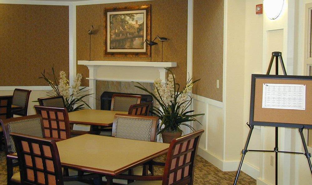 A cozy dining area with tables and chairs, featuring a fireplace and decorative plants.