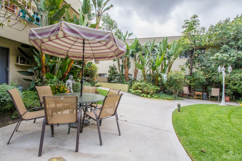 A tranquil backyard patio with seating area and lush greenery.