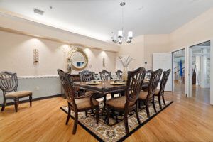 A elegantly designed dining room featuring a large wooden table surrounded by chairs, a chandelier, and decorative elements like a mirror on the wall.