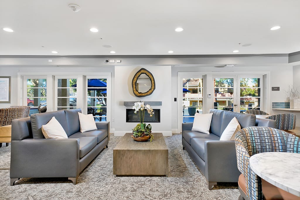 A modern living room with sleek sofas, a central coffee table, and a decorative fireplace.