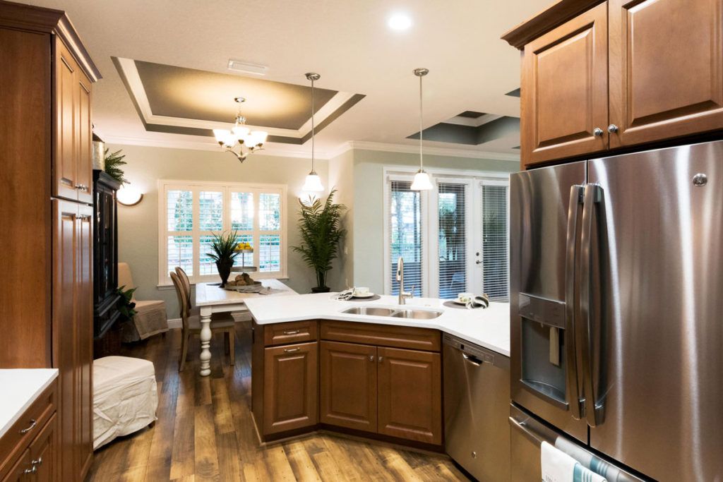 A modern kitchen and dining area featuring wooden cabinets, stainless steel appliances, and elegant lighting.