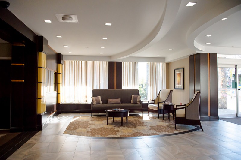 A modern living room with stylish furniture, including a sofa, armchairs, and a coffee table on a decorative carpet.