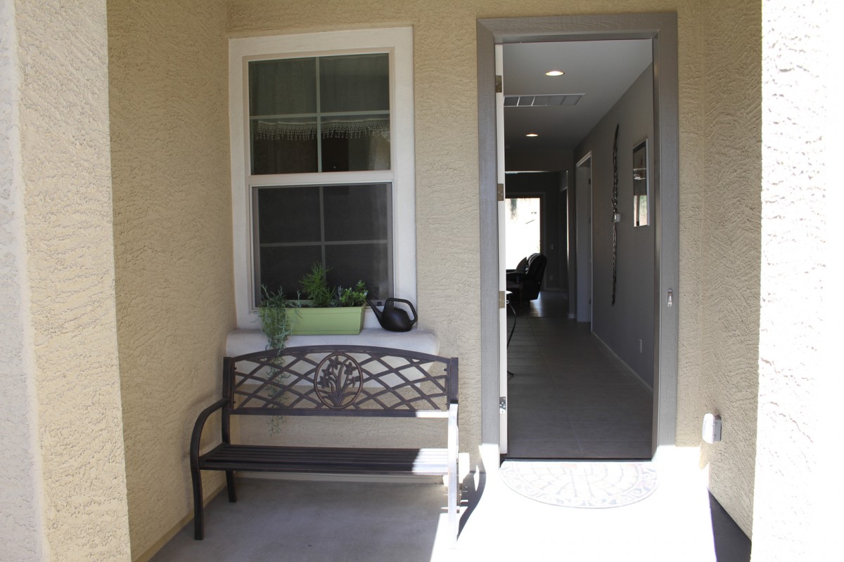 A bench and potted plant are positioned outside a doorway leading to a well-lit hallway.