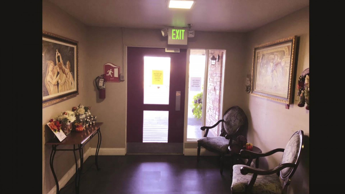 A small room with an exit door, chairs, and decorative items.