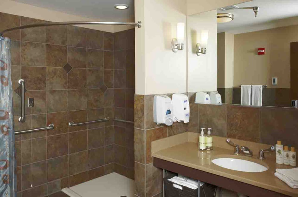 A modern bathroom with a walk-in shower, a sink with a mirror, and elegant tile walls.