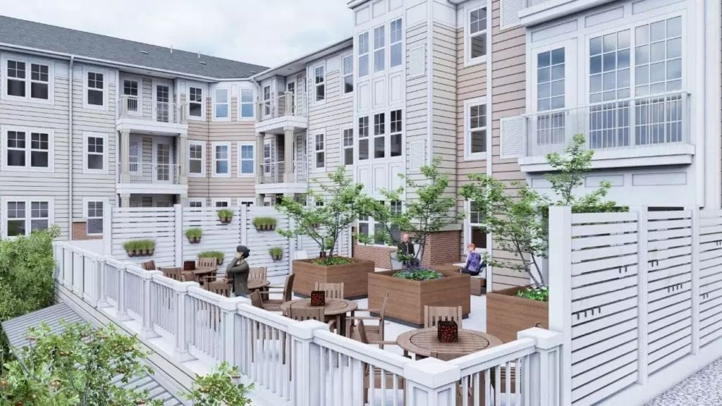 A modern apartment complex with an inviting outdoor patio area featuring seating and decorative plants.