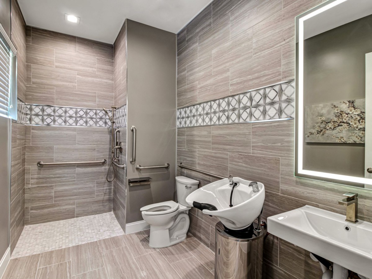 A modern bathroom with a sleek design featuring a toilet, sink, and decorative tiles.