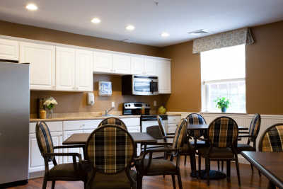 A cozy kitchen and dining area featuring a table with chairs, white cabinets, and a microwave.