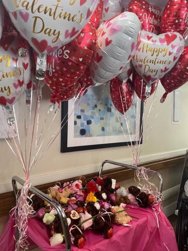 A festive display of Valentine's Day balloons and teddy bears arranged on a cart, ready for celebration.